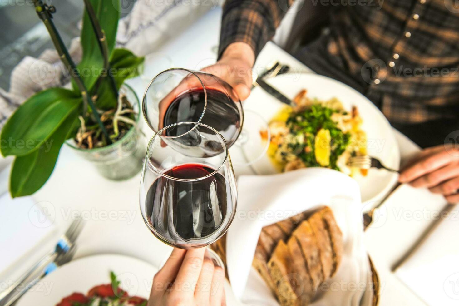 Due ospiti nel un' ristorante siamo festeggiare un anniversario e tintinnante vino occhiali. foto