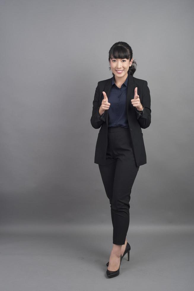 donna d'affari sorridente in blazer su sfondo grigio foto