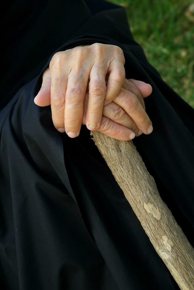 il mani di un vecchio donna su un' di legno bastone foto