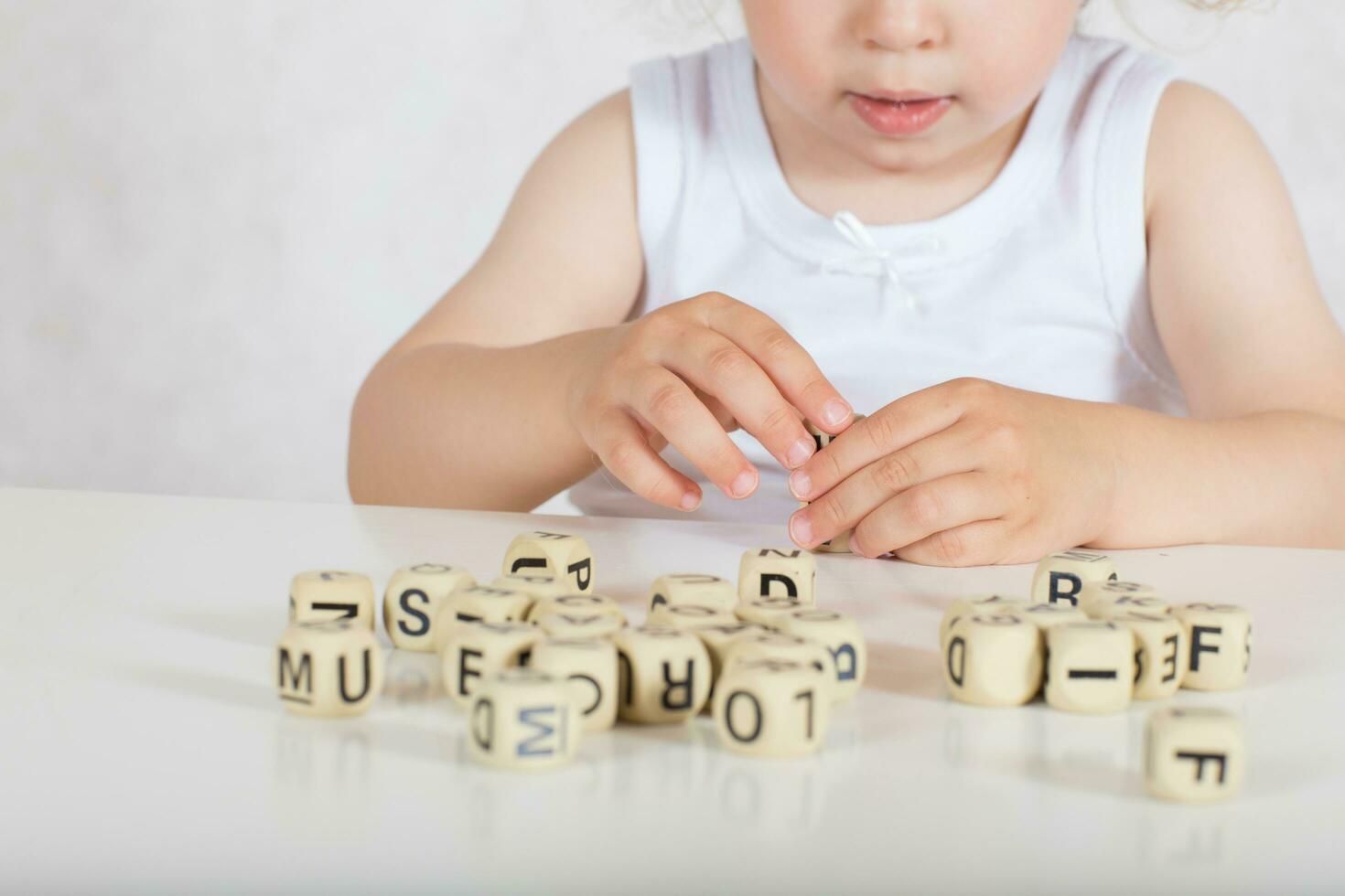 piccolo ragazza compone parole a partire dal lettere. avvicinamento foto