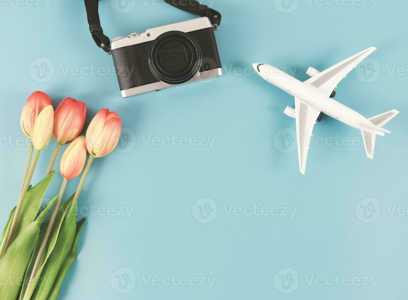 piatto posare di aereo modello, digitale telecamera e tulipani fiori su blu sfondo con copia spazio. foto