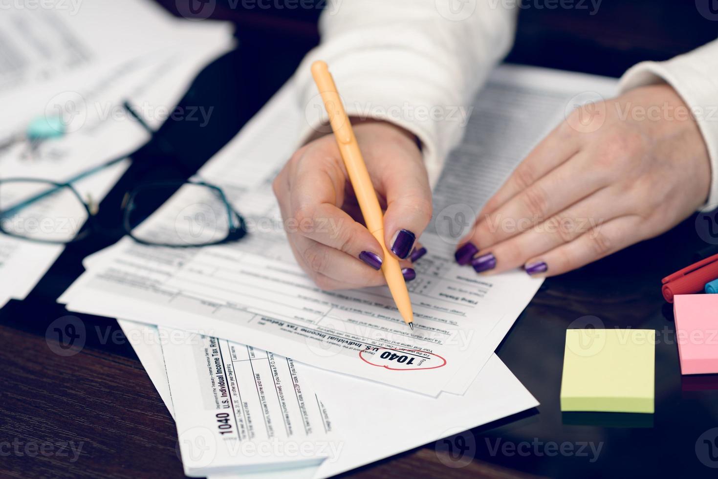 la donna riempie il modulo fiscale, lavorando con i documenti fiscali. modulo 1040 modulo dichiarazione dei redditi individuale. moduli fiscali degli stati uniti. moduli fiscali americani vuoti. tempo fiscale. foto