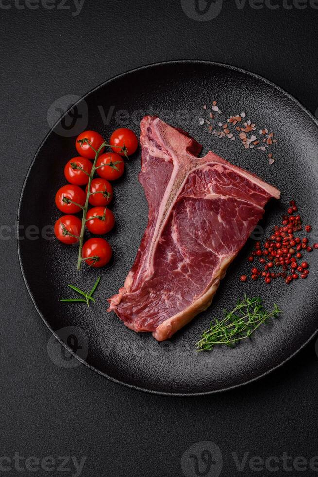 crudo succoso Manzo t-bone bistecca con sale, spezie e erbe aromatiche foto