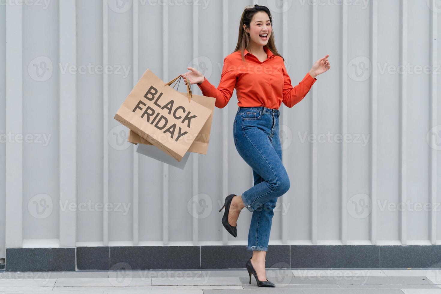 ritratto all'aperto di donna felice che tiene le borse della spesa e faccina sorridente al centro commerciale foto