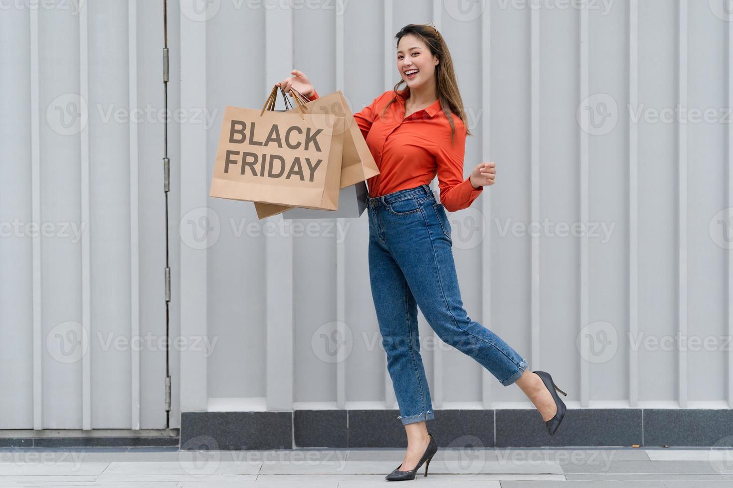 ritratto all'aperto di donna felice che tiene le borse della spesa e faccina sorridente al centro commerciale foto