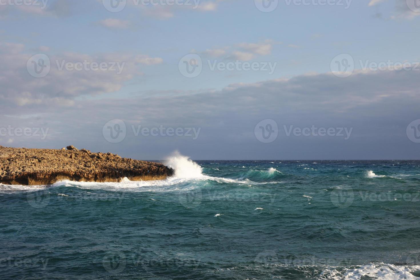 onde che colpiscono le scogliere rocciose in una spiaggia situata a Cipro, questo tempo potrebbe essere pericoloso per gli sport acquatici, ma allo stesso tempo le onde e i loro spruzzi sono belli e selvaggi. foto