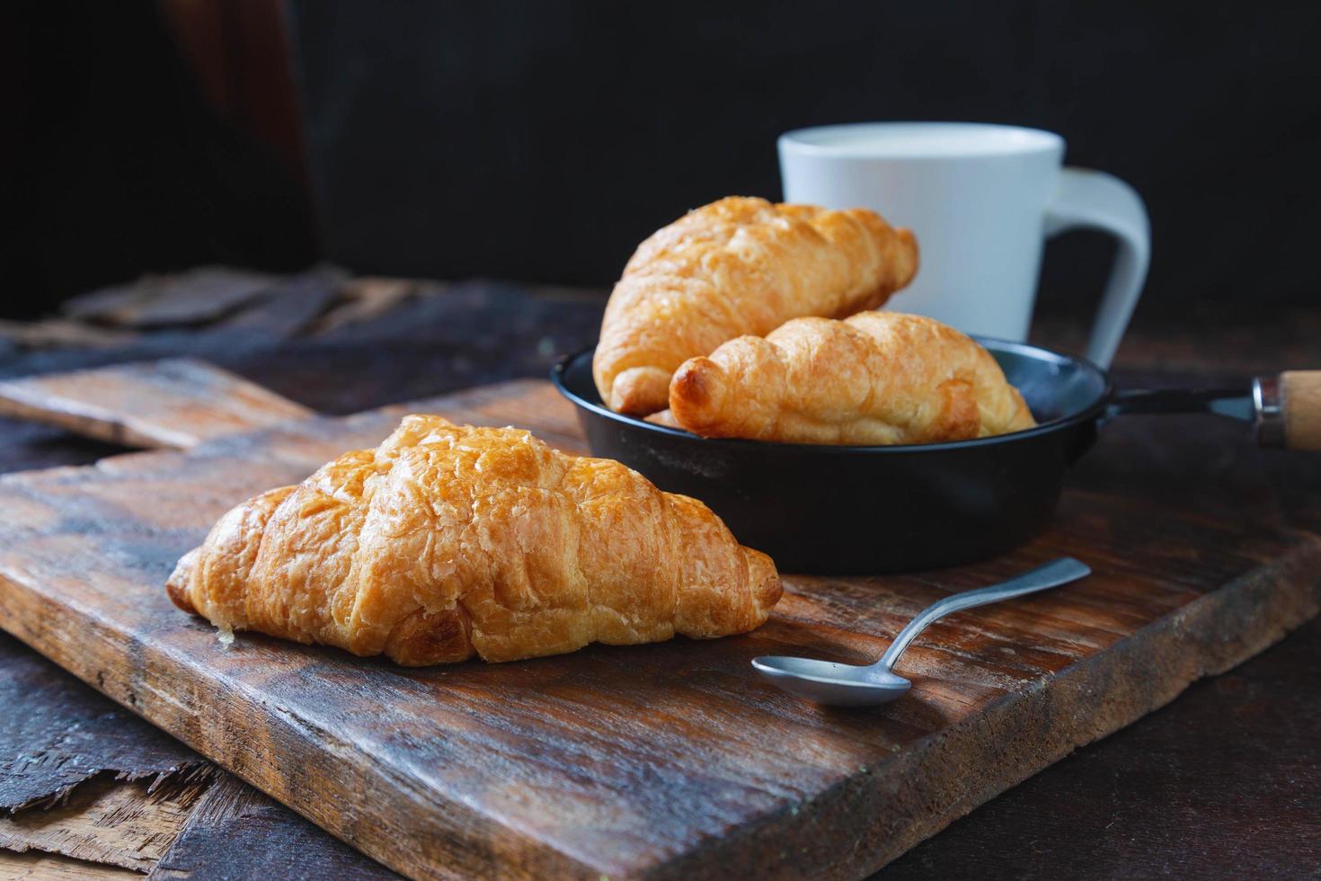 pane per la colazione, croissant e latte fresco sul tavolo di legno. foto