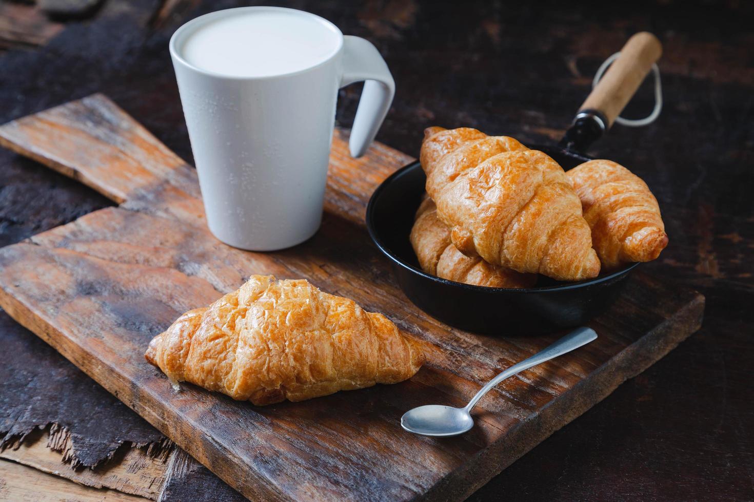 pane per la colazione, croissant e latte fresco sul tavolo di legno. foto