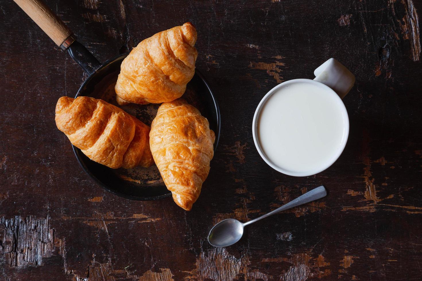 pane per la colazione, croissant e latte fresco sul tavolo di legno. foto