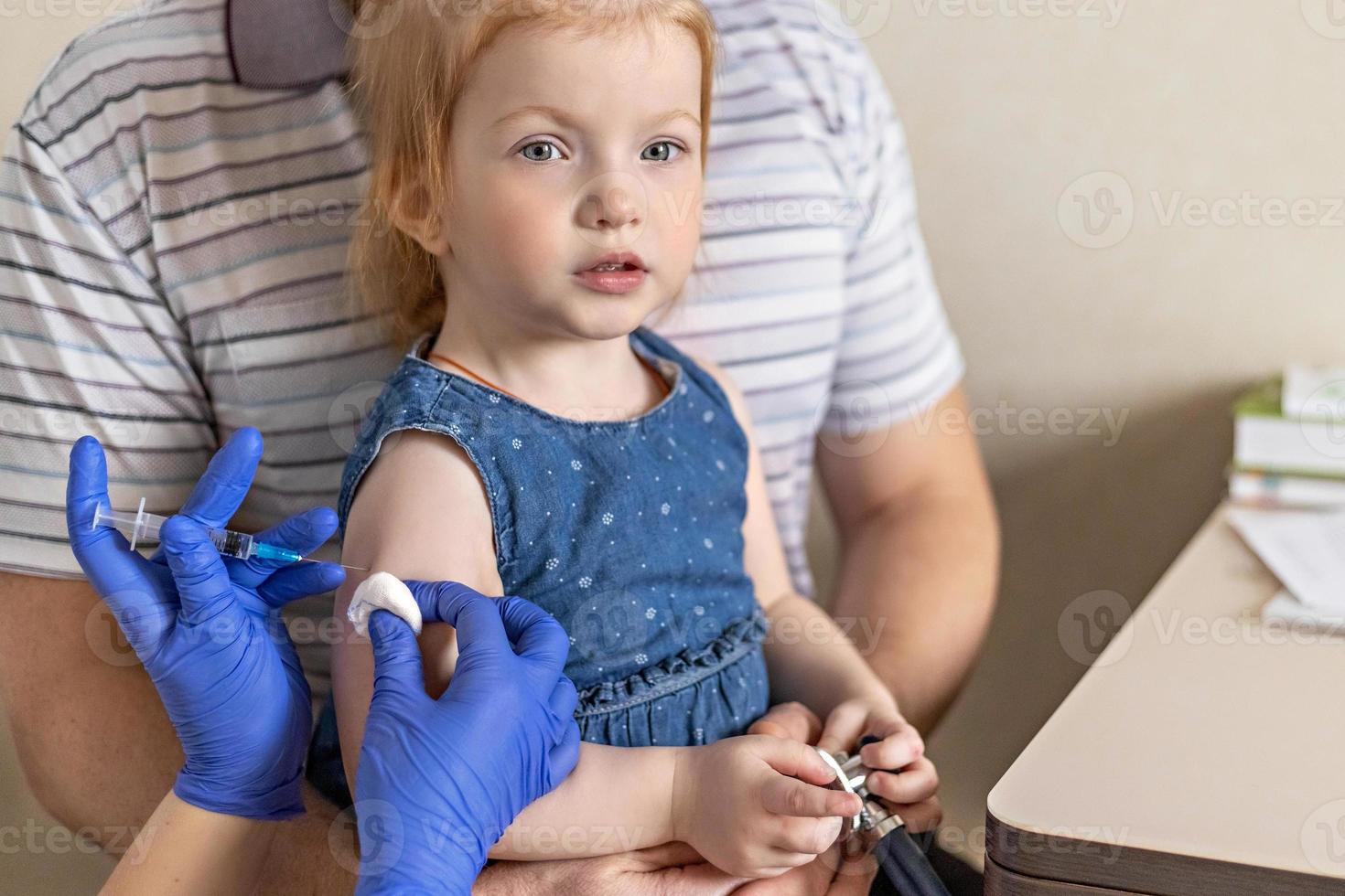 una bambina con suo padre nell'ambulatorio della clinica viene vaccinata contro il coronavirus.il concetto di vaccinazione, immunizzazione, prevenzione contro covid-19. foto