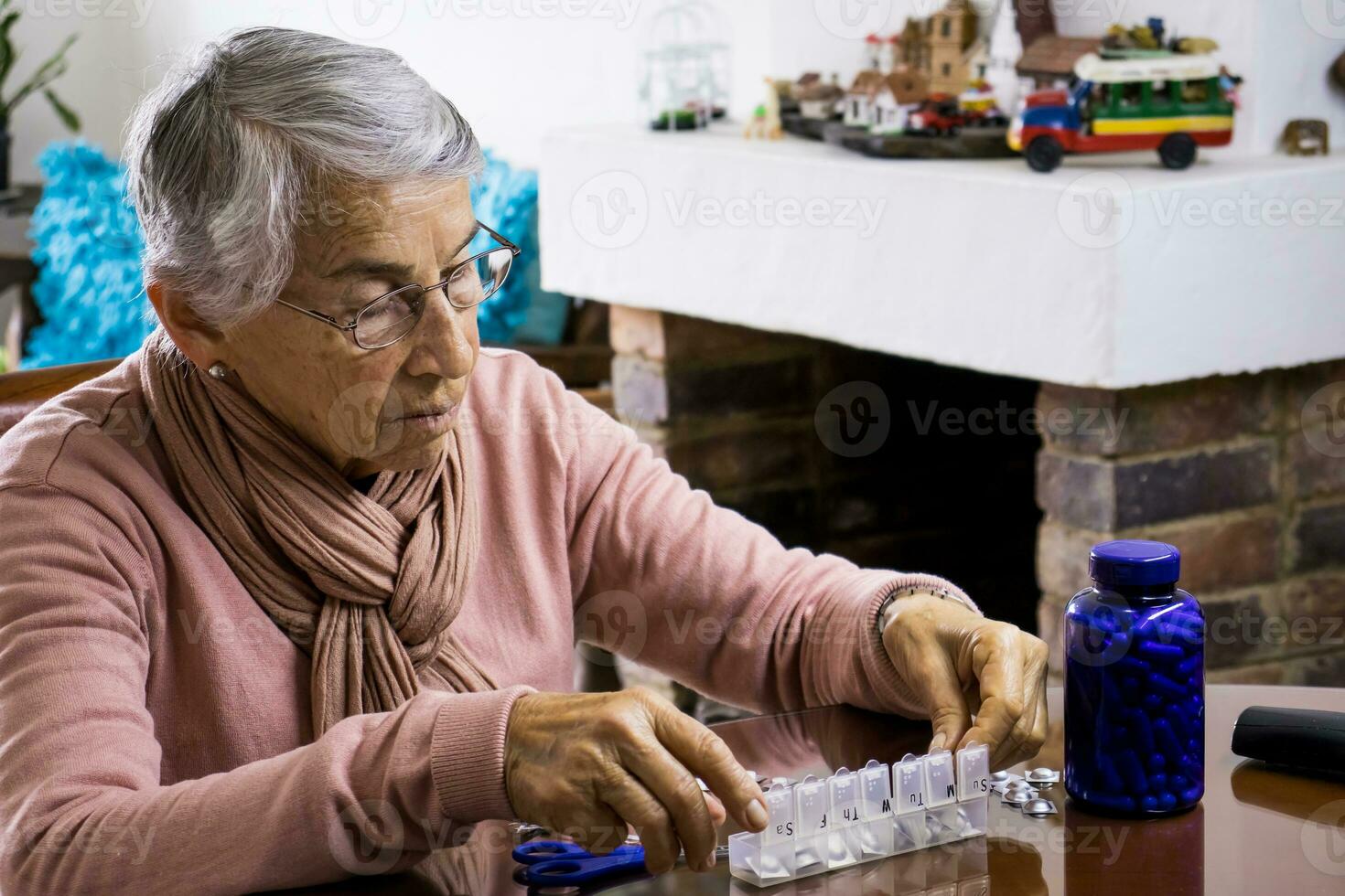 anziano donna a casa organizzazione sua prescrizione farmaci in un' settimanalmente pillola organizzatore foto