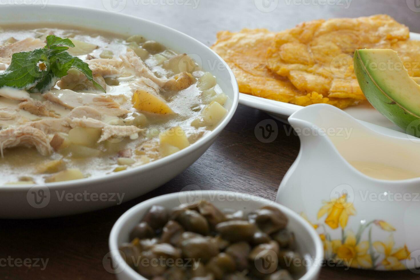 tradizionale colombiano ajiaco servito con patacono, avocado e capperi foto