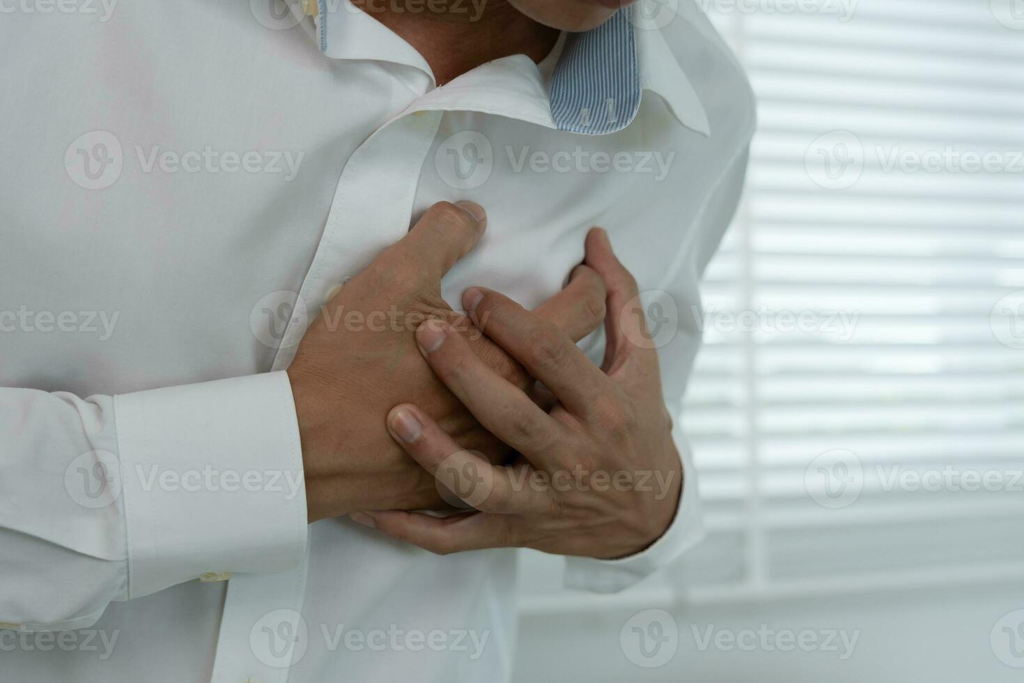 mano hold il petto con cuore attacco sintomi, asiatico uomo avere il petto dolore causato di cuore patologia, perdere, dilatazione, allargata coronario cuore, stampa su il il petto con un' doloroso espressione foto