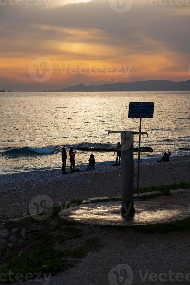 scena al tramonto di sagome di persone sulla spiaggia di paleo faliro ad atene, in grecia foto