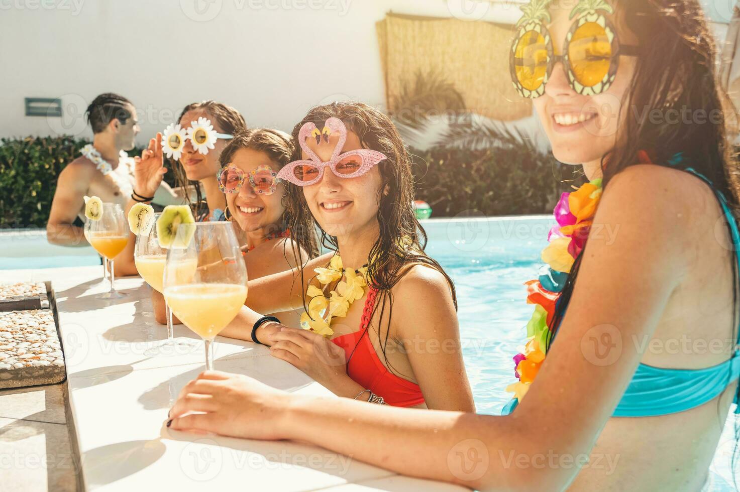 gruppo di amici nel costume da bagno bevanda un' cocktail nel un' nuoto piscina foto