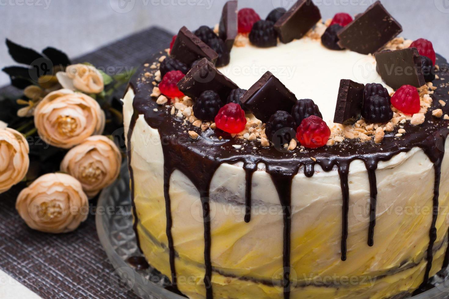 bella torta festiva con glassa al cioccolato e marmellata su uno sfondo di fiori foto