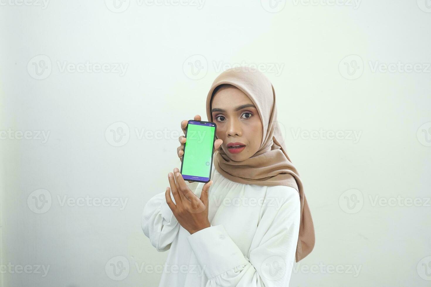 eccitato bellissimo asiatico musulmano donna mostrando verde schermo mobile Telefono isolato al di sopra di bianca sfondo foto