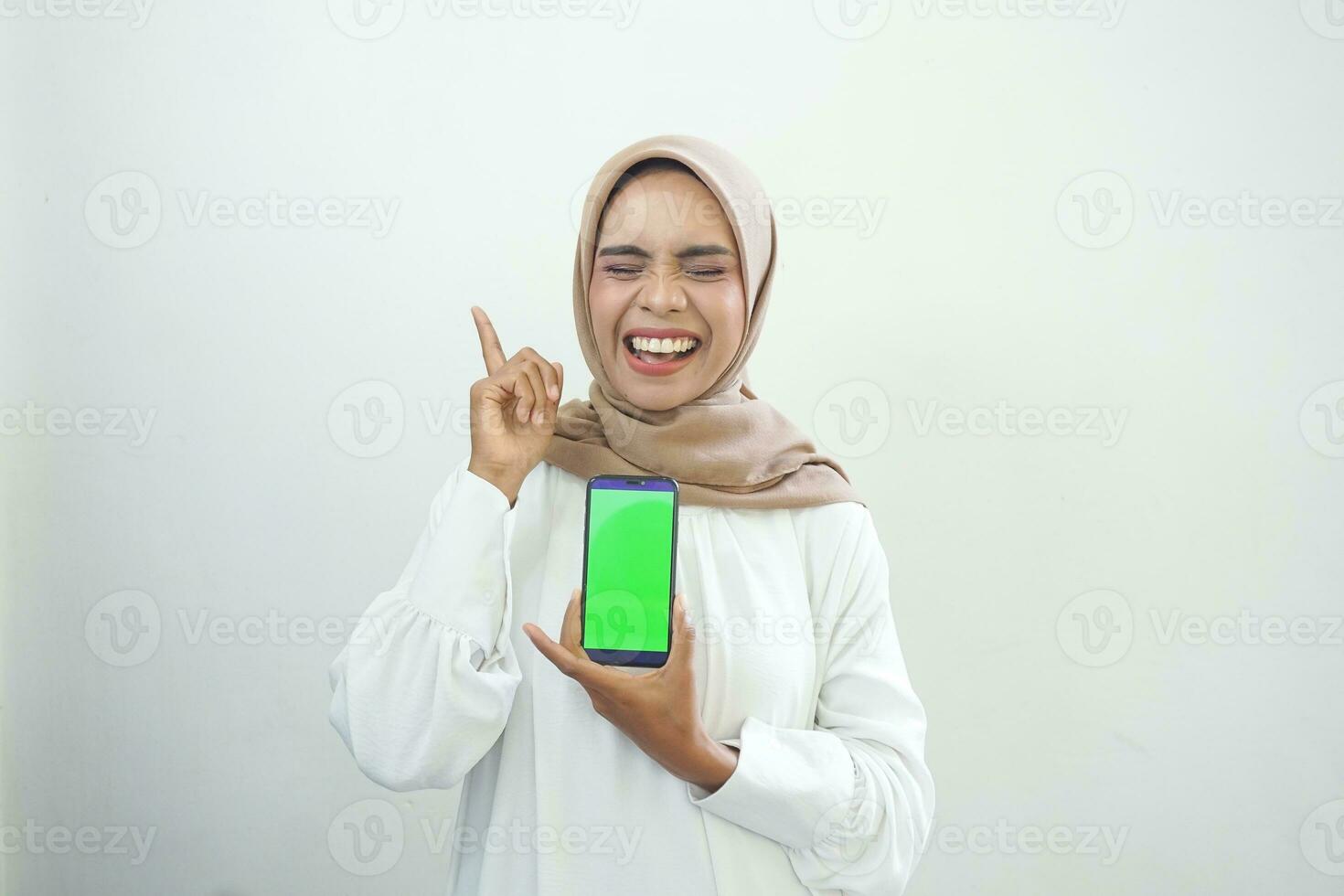 eccitato bellissimo asiatico musulmano donna mostrando verde schermo mobile Telefono isolato al di sopra di bianca sfondo foto