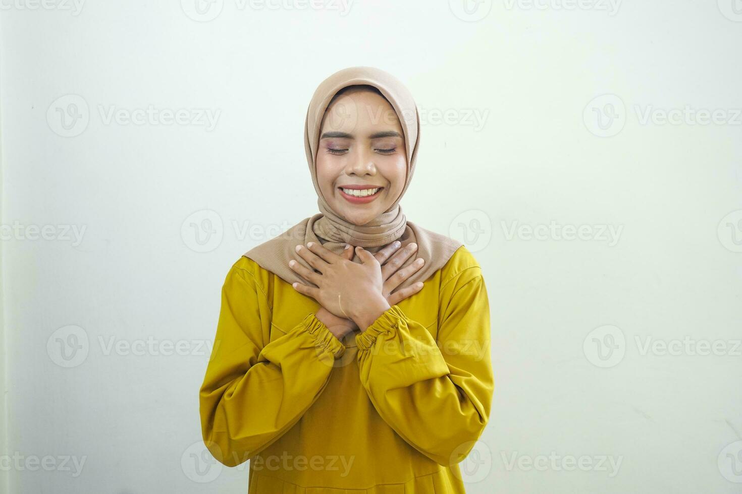 felicissimo bellissimo asiatico donna nel casuale camicia Tenere mani su sua il petto isolato al di sopra di bianca sfondo foto