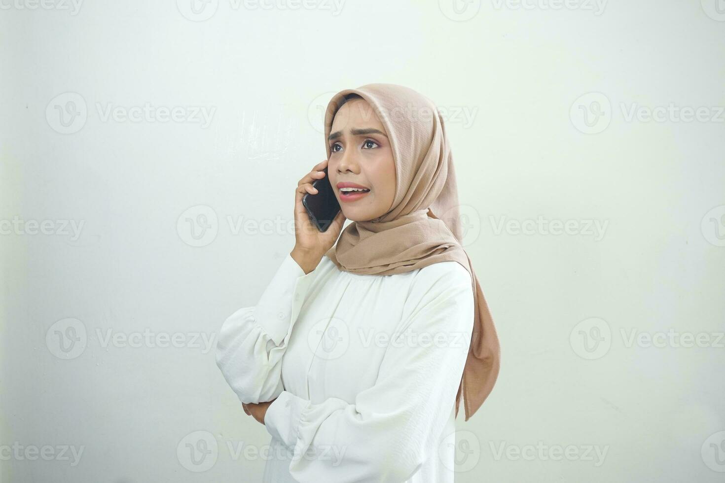 bellissimo sorpreso asiatico musulmano donna indossare hijab utilizzando un' mobile Telefono, digitando sms Messaggio isolato su bianca sfondo studio ritratto. persone religioso stile di vita concetto foto