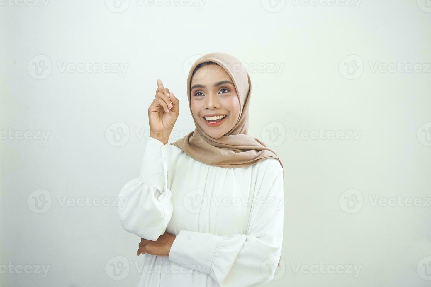 ritratto di sorridente giovane asiatico donna guardare su e tocchi sua guancia isolato su bianca sfondo foto