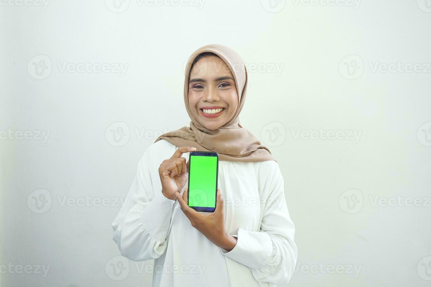 eccitato bellissimo asiatico musulmano donna mostrando verde schermo mobile Telefono isolato al di sopra di bianca sfondo foto