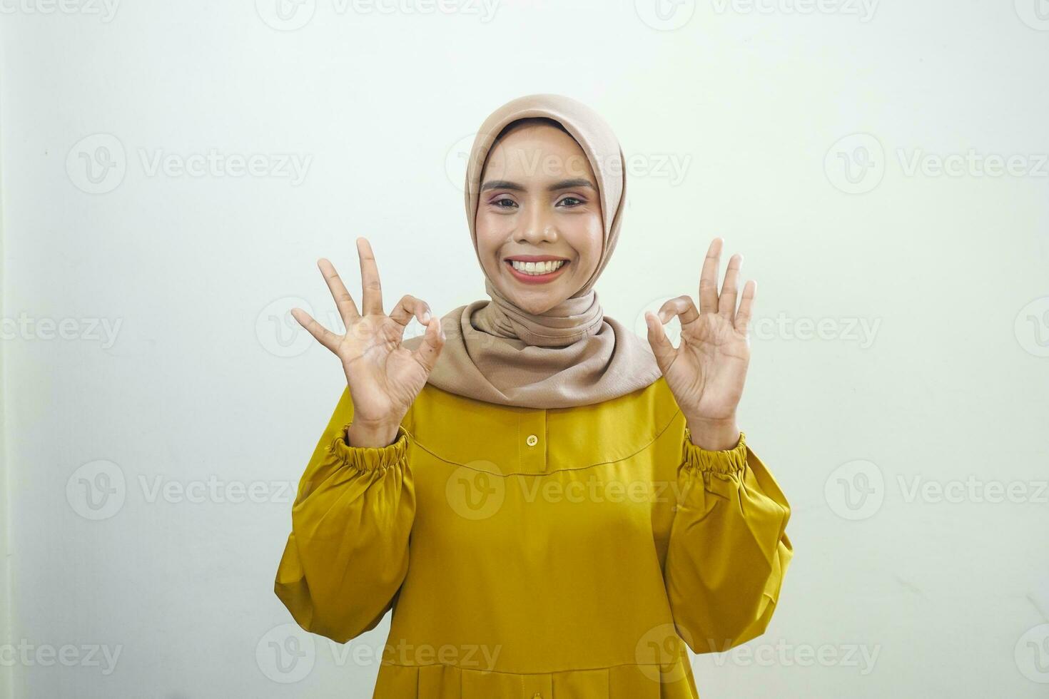 sorridente giovane asiatico donna nel bianca casuale mostrando va bene gesto isolato su bianca sfondo foto