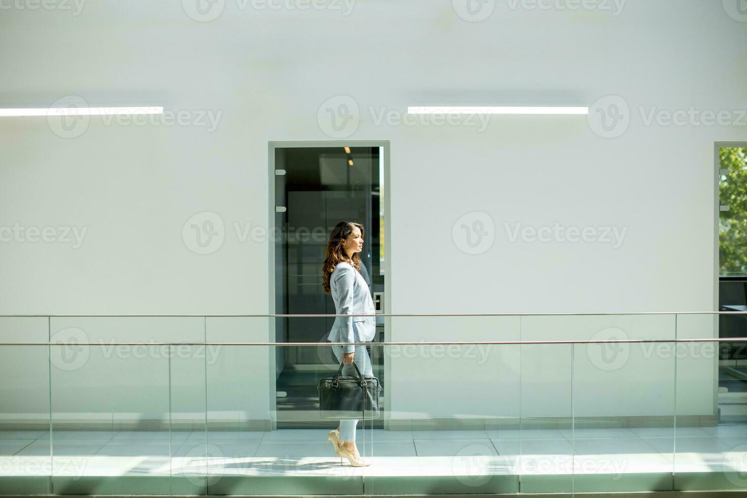 bella giovane attività commerciale donna a piedi con ventiquattrore nel il ufficio corridoio foto