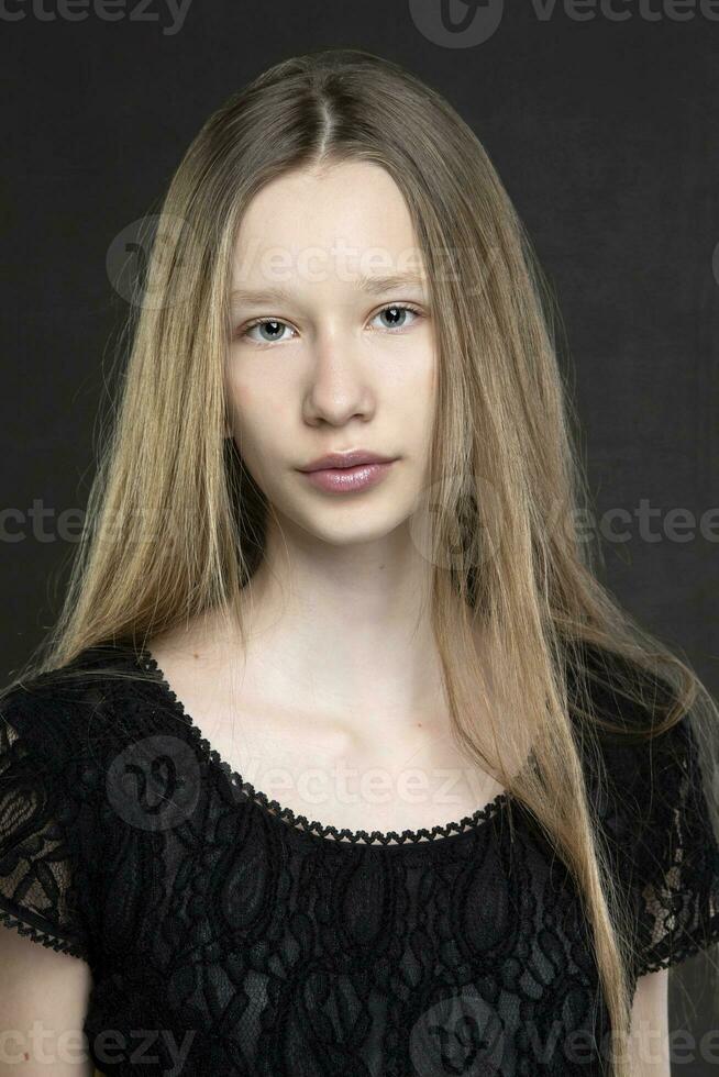 bellissimo adolescente ragazza con lungo capelli su un' grigio sfondo. un' ragazza con un' europeo viso genere. foto