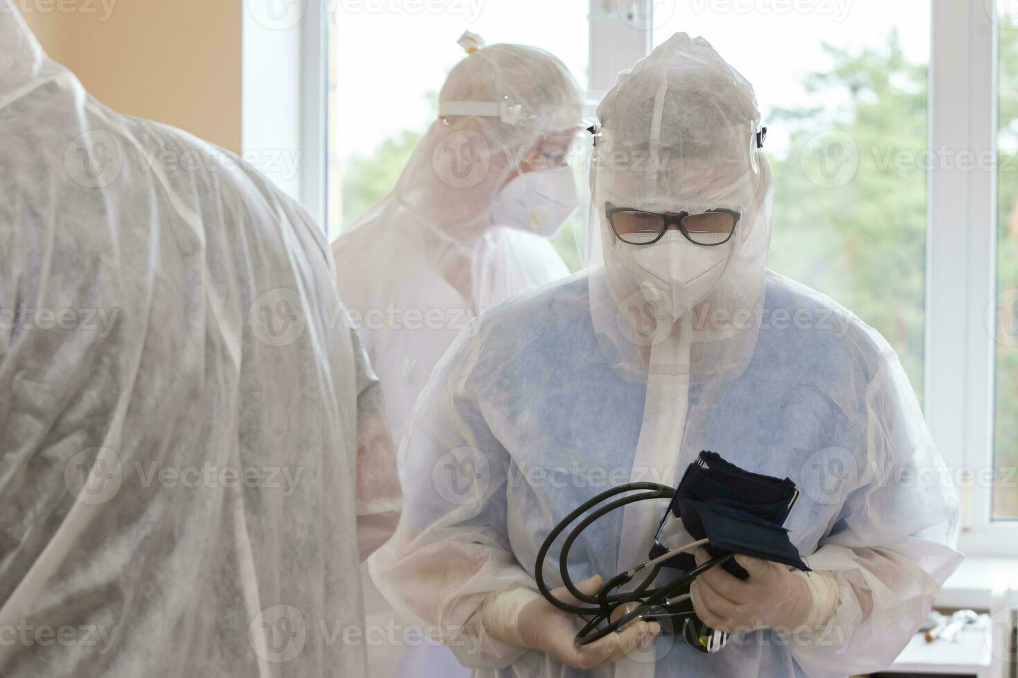medici nel protettivo tute con un' medico tonometro durante il coronavirus epidemico. foto