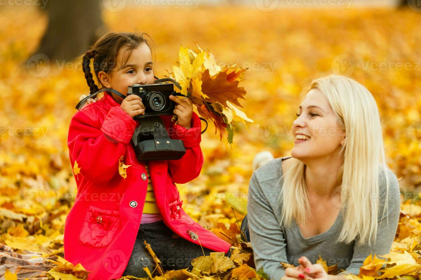 madre e figlia dire bugie su il le foglie a il autunno parco. foto