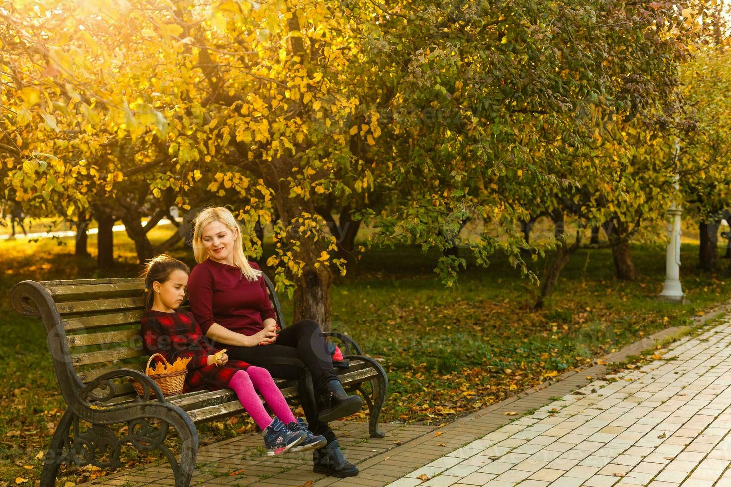 contento madre e figlia Abbracciare una persona su un' panchina nel un autunno parco foto