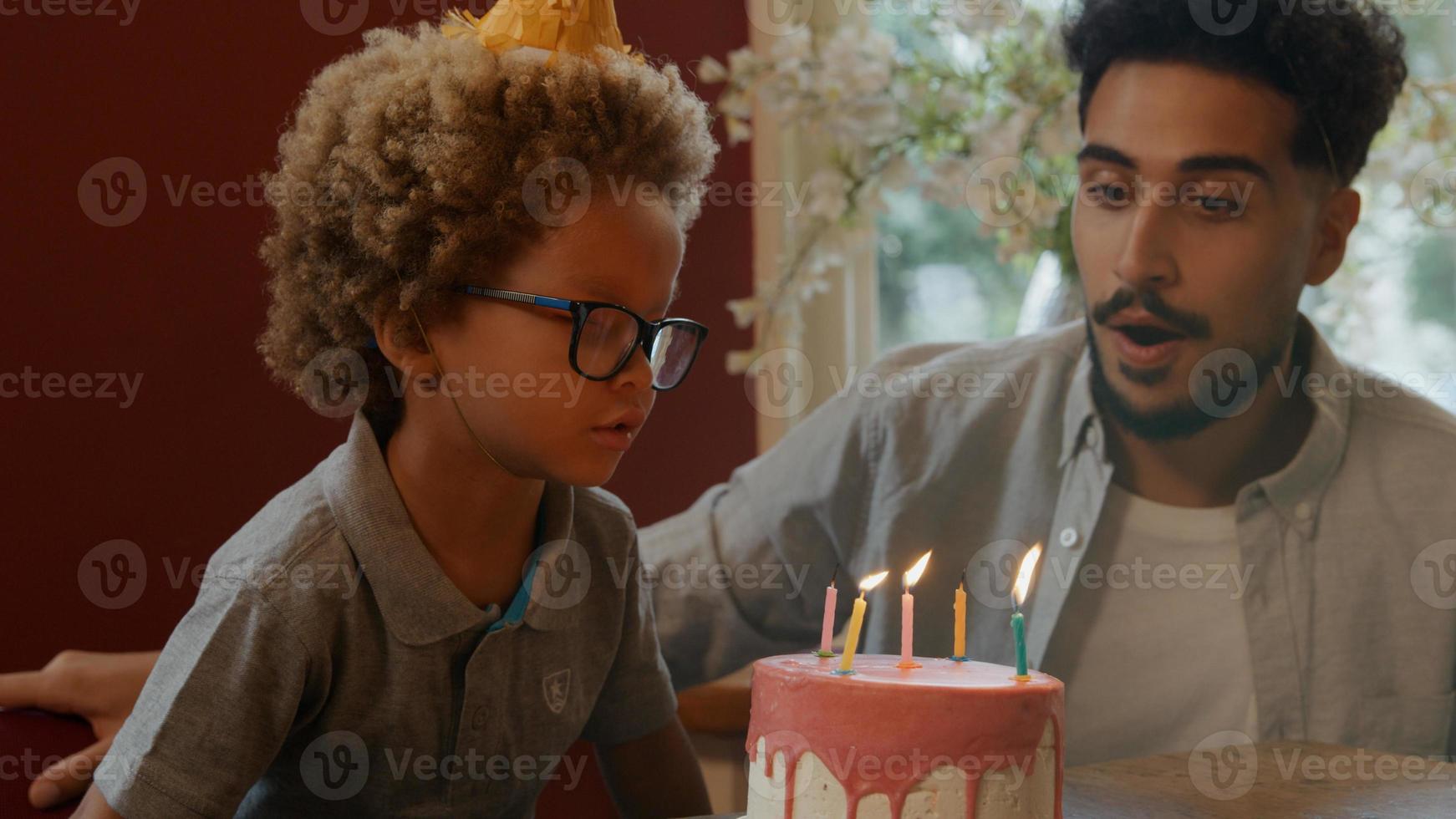 ragazzo che spegne le candeline sulla torta con la famiglia a guardare foto