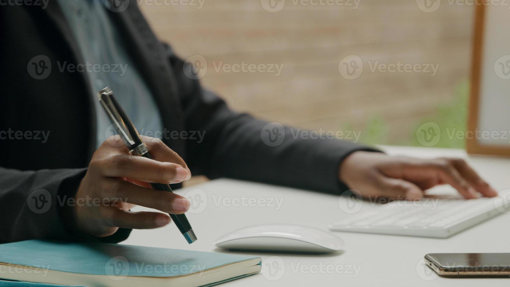 Close up della donna che lavora con la tastiera del computer e la penna foto