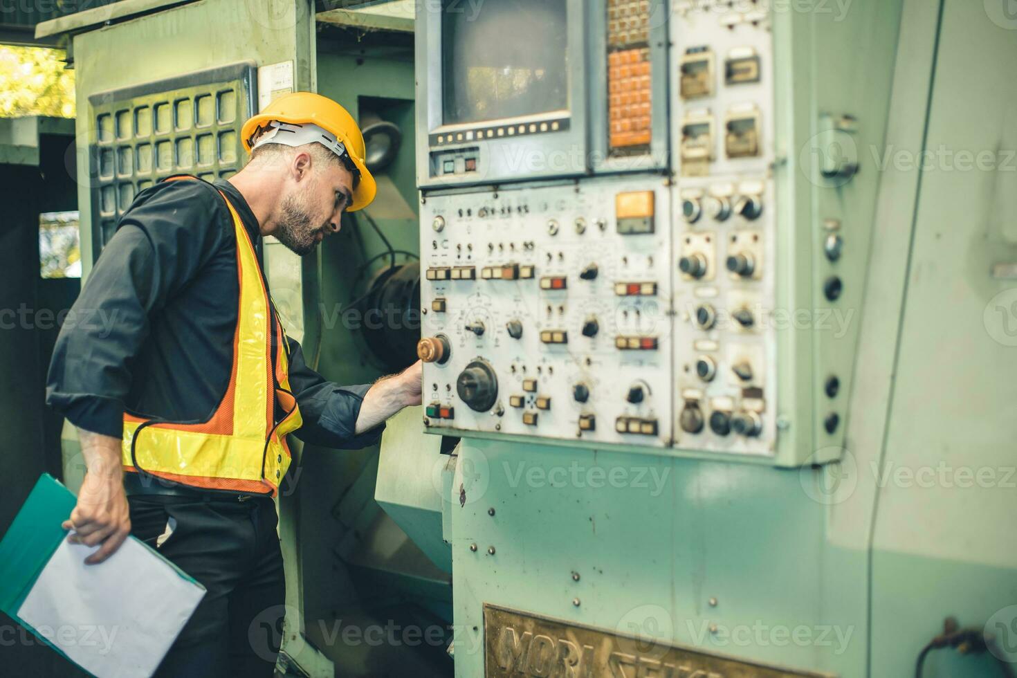 giovane ingegnere maschio lavoratore opera dai un'occhiata servizio vecchio cnc tornio macchina nel pesante metallo industria foto