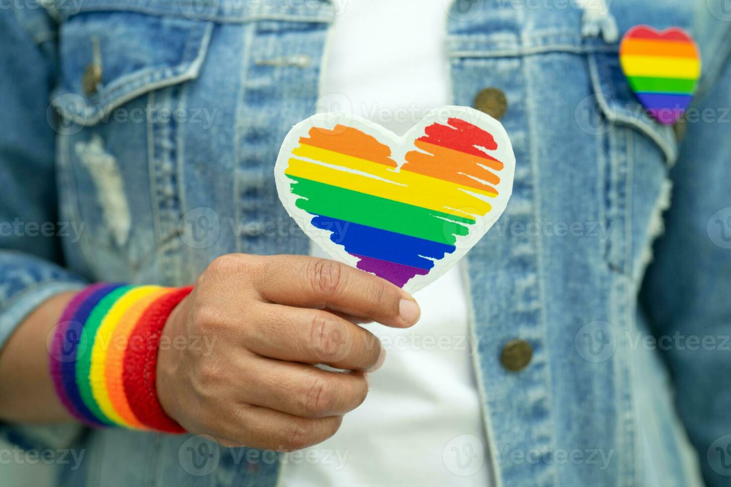 la signora asiatica che indossa braccialetti con bandiera arcobaleno e tiene il cuore rosso, simbolo del mese dell'orgoglio lgbt celebra l'annuale a giugno sociale di gay, lesbiche, bisessuali, transgender, diritti umani. foto