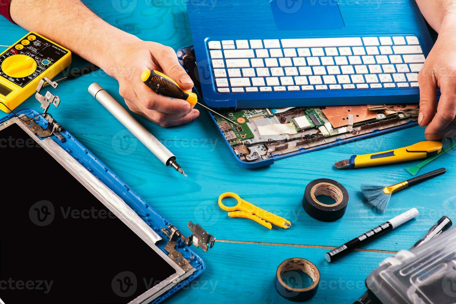 la procedura guidata ripara il computer portatile con gli strumenti e le mani sul tavolo di legno blu. vista dall'alto foto