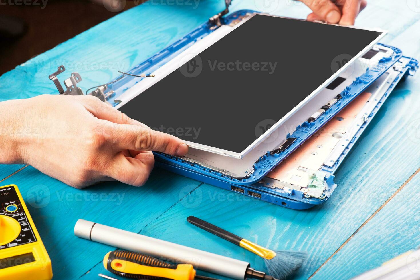 la procedura guidata ripara il computer portatile con gli strumenti e le mani sul tavolo di legno blu. vista dall'alto foto