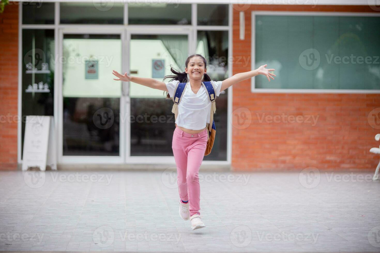 indietro per scuola. carino asiatico bambino ragazza con un' zaino in esecuzione e andando per scuola con divertimento foto