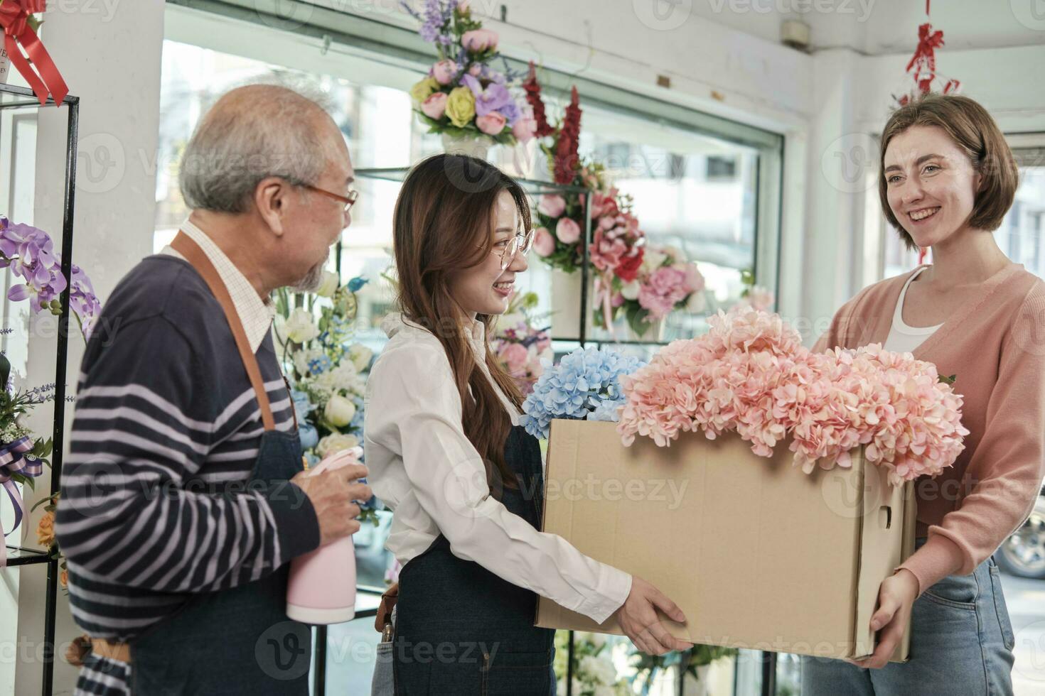 giovane bellissimo femmina fioraio lavoratore con vecchio proprietario consegna fresco flore per bianca cliente chi acquistato ordine, sorridente con contento opera nel colorato fiore negozio, piccolo attività commerciale pmi imprenditore. foto