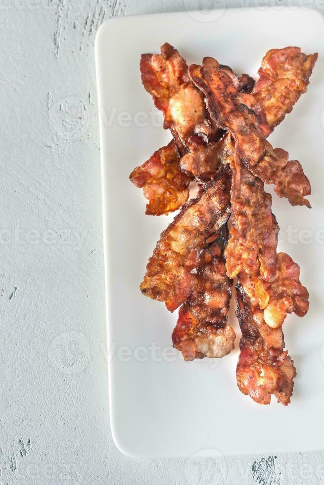 fritte Bacon strisce su il bianca piatto foto