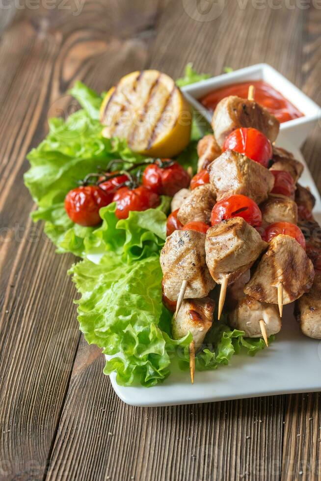 spiedini di pollo alla griglia sul piatto bianco foto