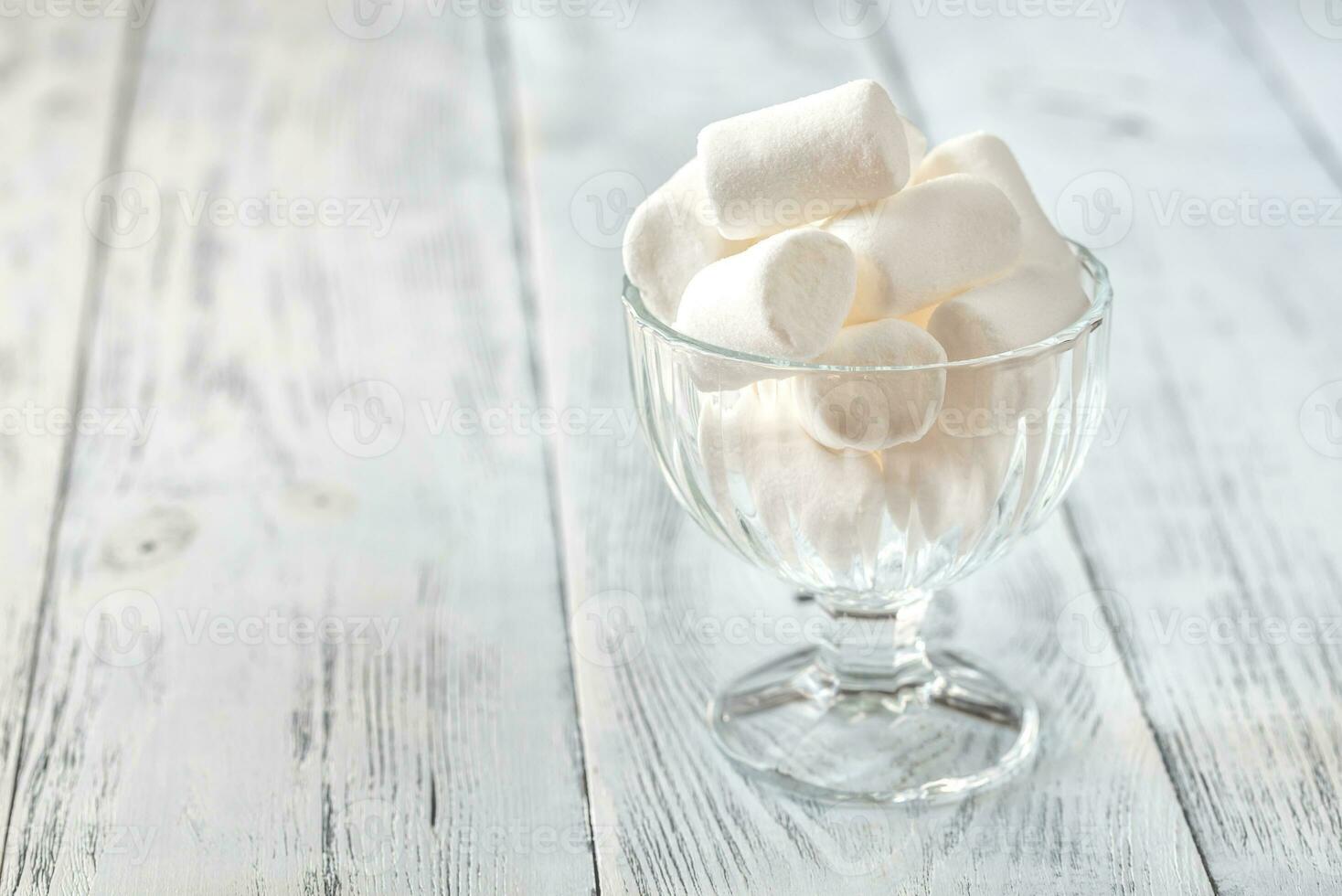 bicchiere ciotola di marshmallows su il di legno sfondo foto