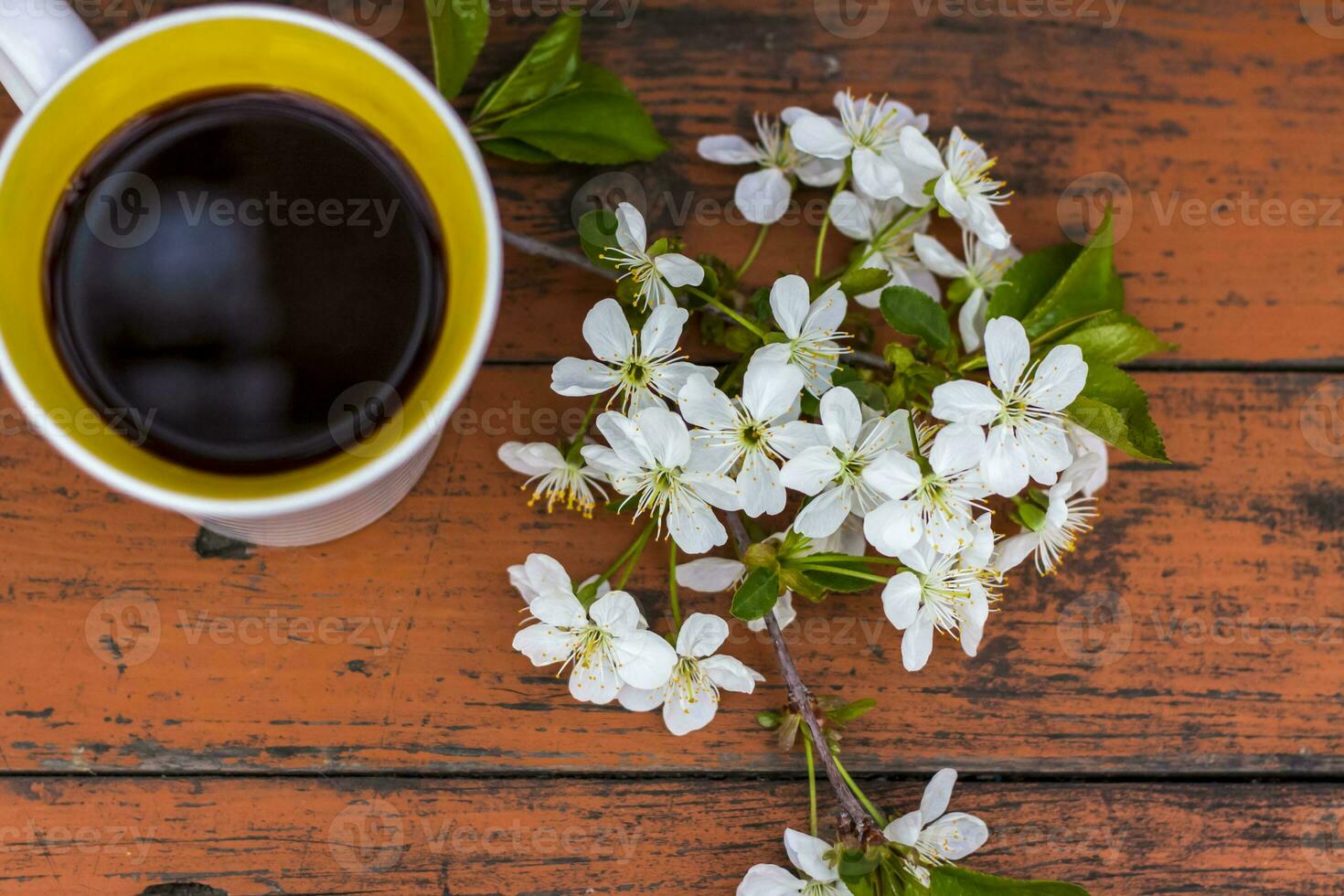 un' tazza di caffè su un' scuro, logoro rustico di legno tavolo. il composizione è decorato con un' ramoscello con bianca fiori. ciliegia albero fiori. selettivo messa a fuoco. foto