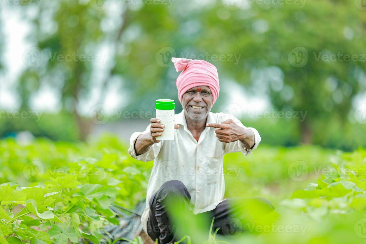 indiano contento contadino Tenere vuoto bottiglia nel mani, contento contadino mostrando bianca bottiglia foto