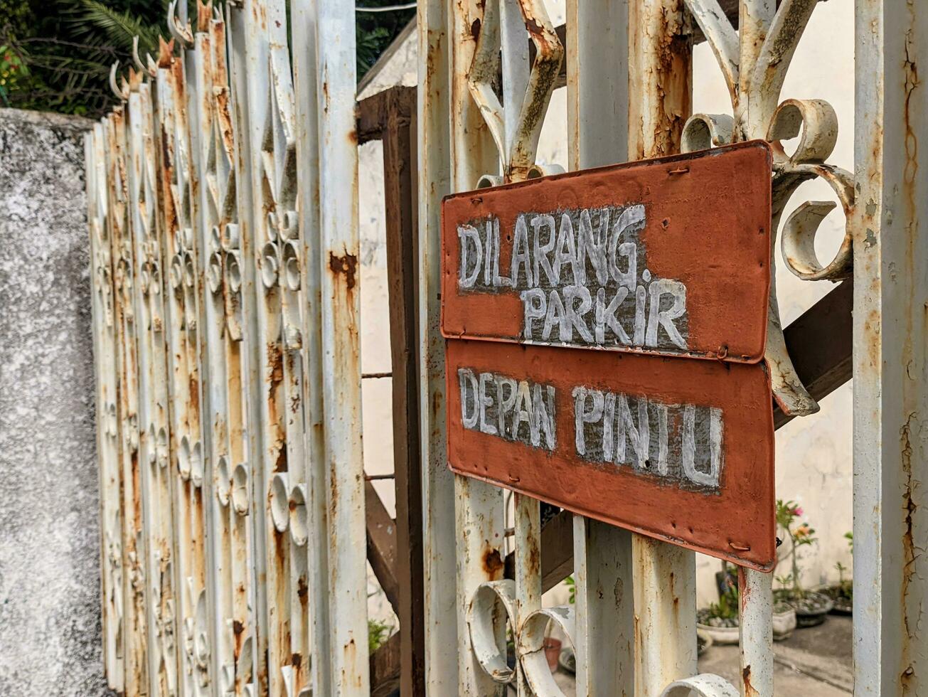 avvertimento cartello con scrittura nel indonesiano no parcheggio nel davanti di porta foto