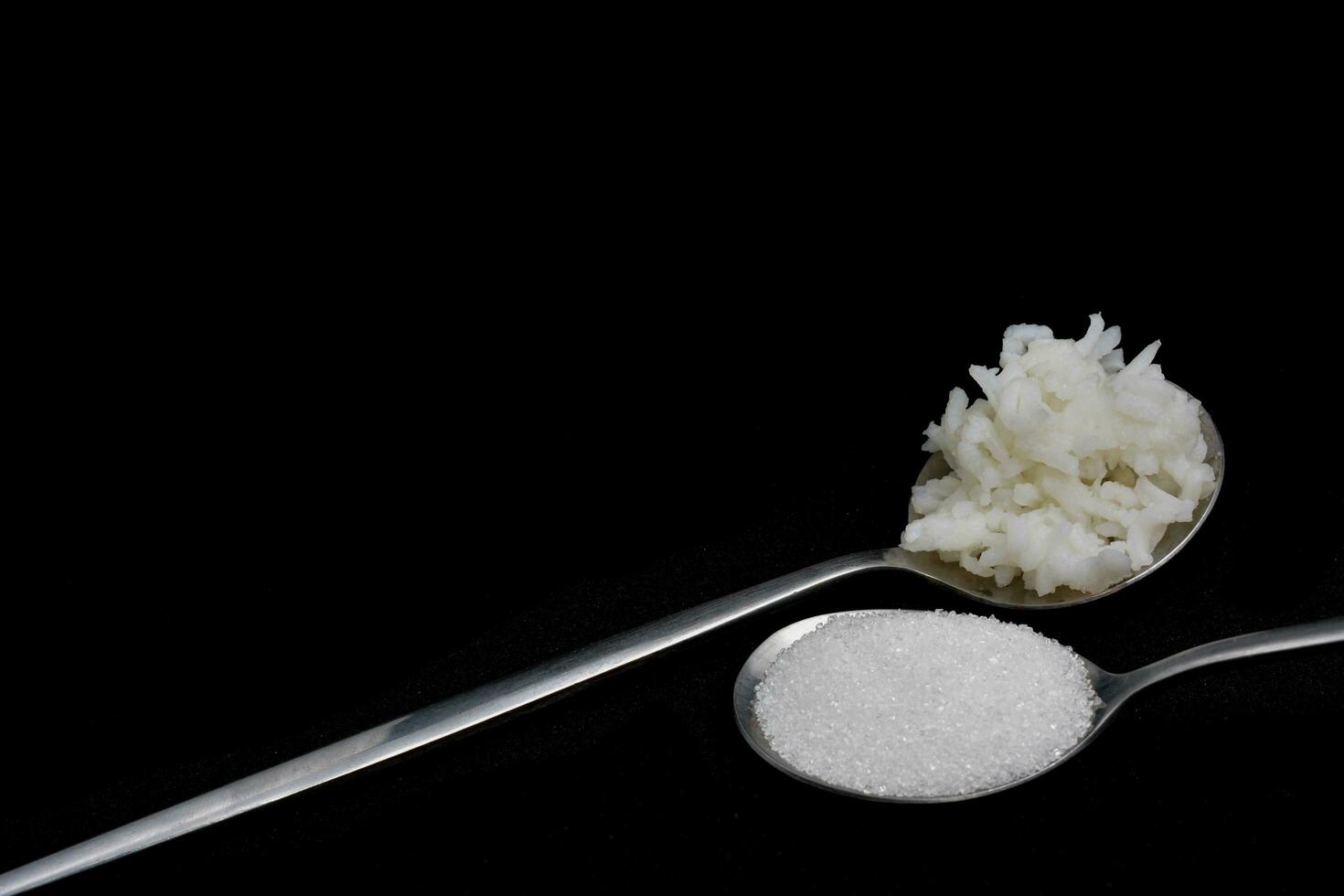 1 cucchiaio di riso e 1 cucchiaio di zucchero stesso quantità di calorie ogni giorno, Due cucchiai, isolato nero sfondo foto