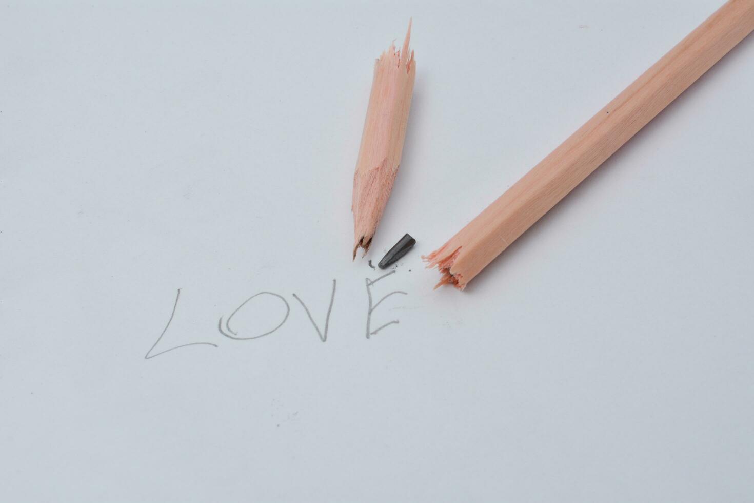 rotto matita. scrittura con un' matita il parola amore. bianca sfondo. foto
