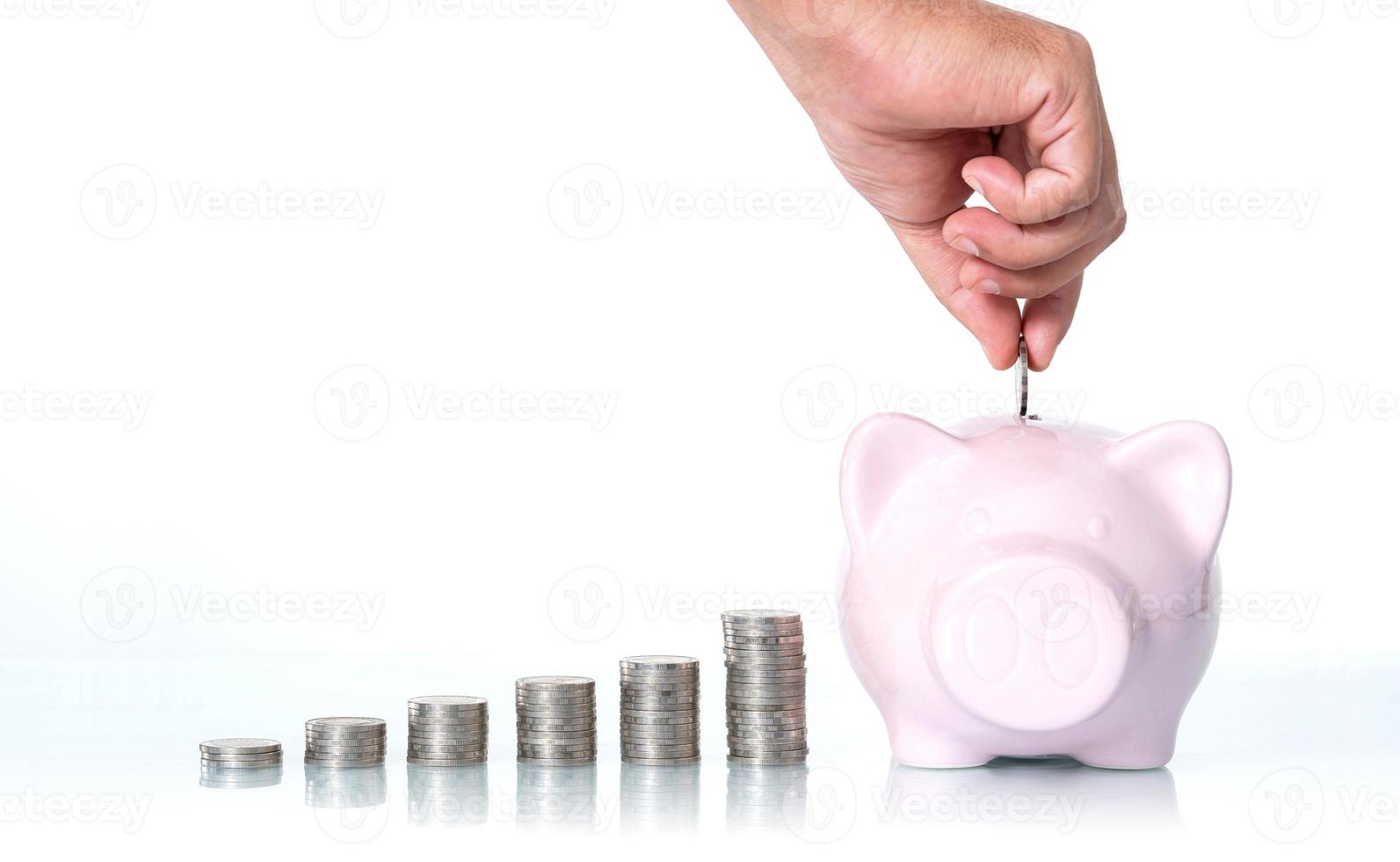 il concetto di risparmio di denaro, mano mettendo una moneta nel salvadanaio su sfondo bianco foto