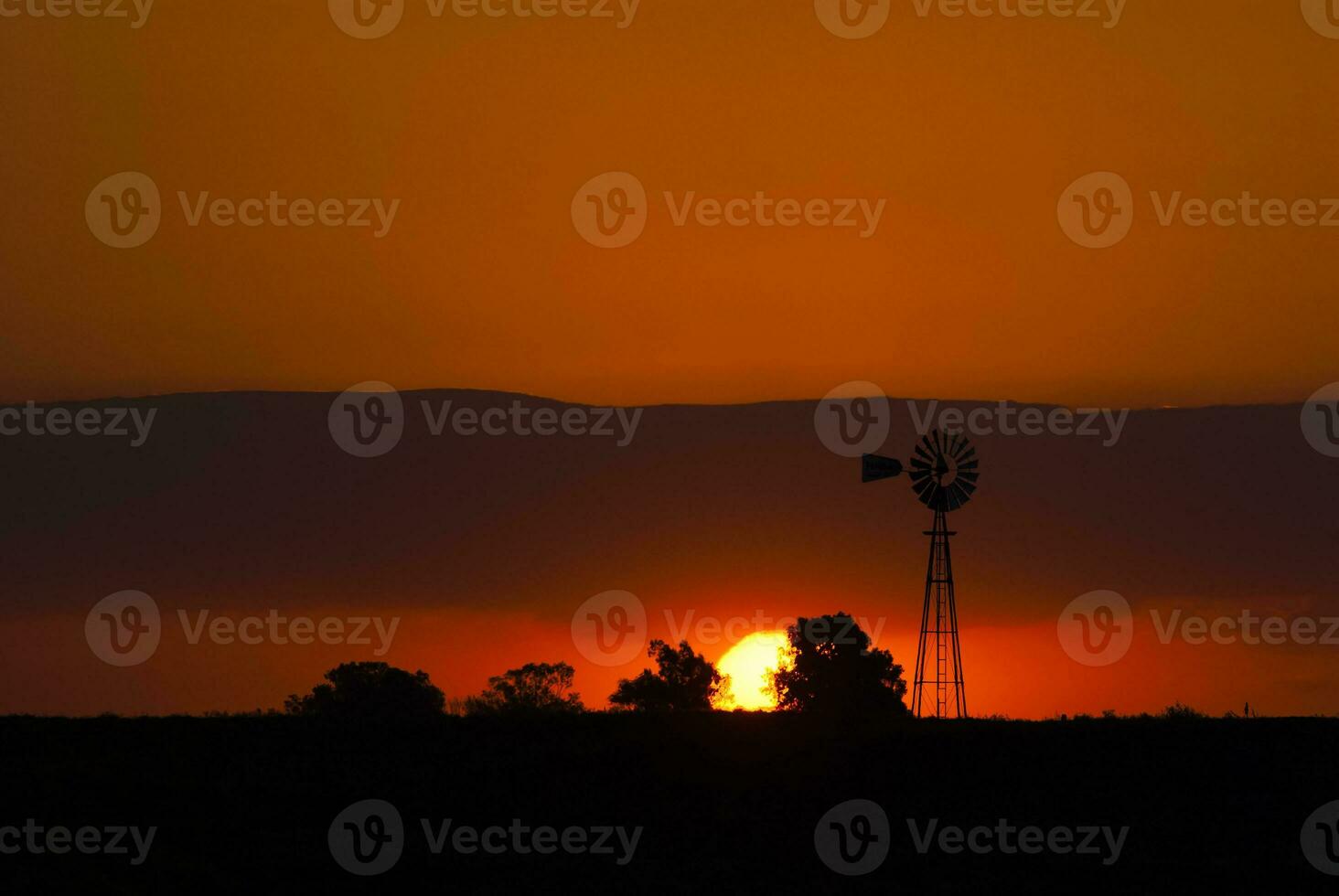 un' mulino a vento e un' tramonto nel il sfondo foto